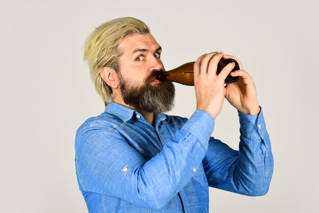 Hipster descansa no bar. Amante do esporte, anime-se. homem maduro segurando uma garrafa de vidro de cerveja. bêbado hippie masculino artesanal cerveja engarrafada. homem feliz segura a garrafa de vidro cheia na mão. masculino segurando a garrafa de cerveja.