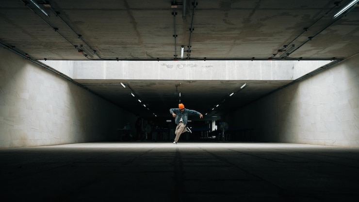 Foto hipster elegante e feliz faz break dance ou passo com o pé no edifício sprightly