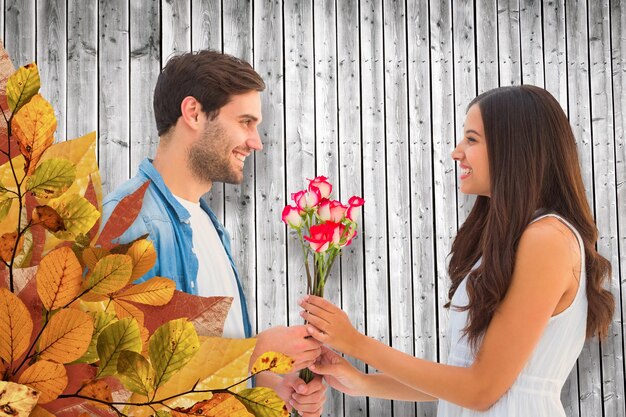 Hipster feliz dando rosas a sua namorada contra pranchas de madeira cinza geradas digitalmente