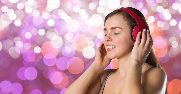 Foto hipster femenino escuchando música en auriculares contra bokeh