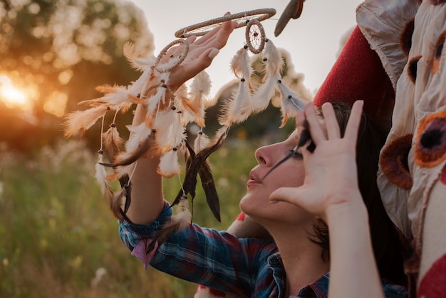 Hipster Frau in Form eines Schamanen sucht Inspiration von Mutter Erde in einem Wigwam in der Natur.