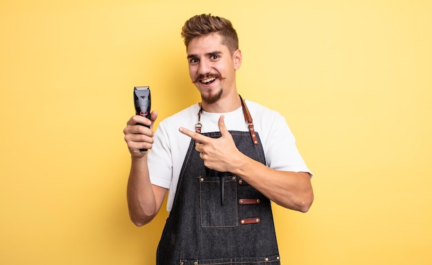 Foto hipster friseur mann sieht aufgeregt und überrascht aus und zeigt auf die seite