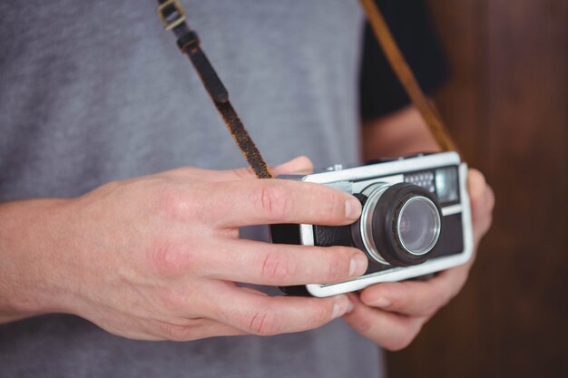 Foto hipster guapo con cámara retro con foco en las manos
