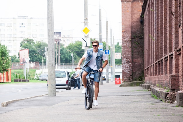 Hipster guapo disfrutando de un paseo por la ciudad en bicicleta.