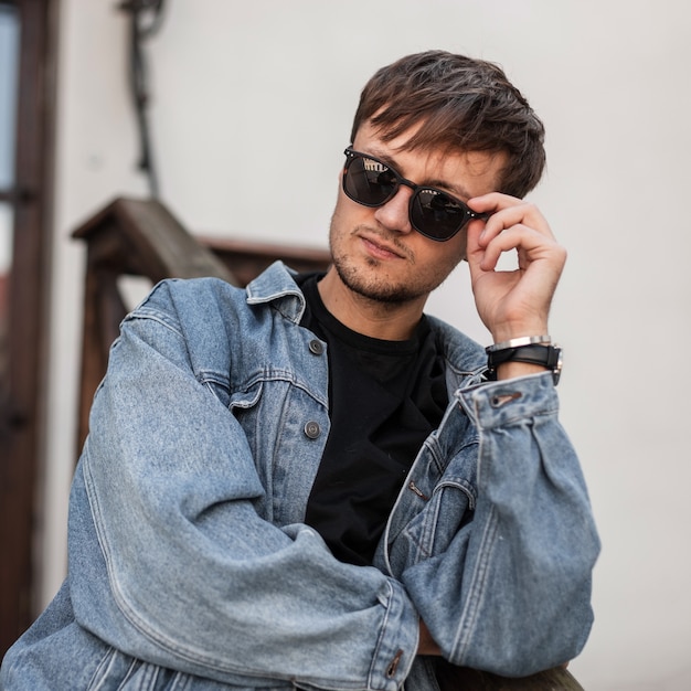 Hipster guapo joven fresco con gafas de sol negras de moda