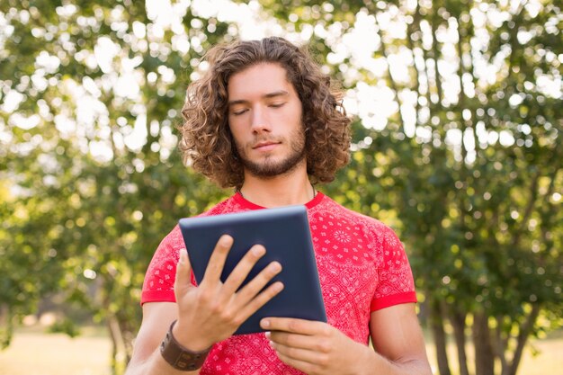 Hipster guapo con tablet pc en el parque