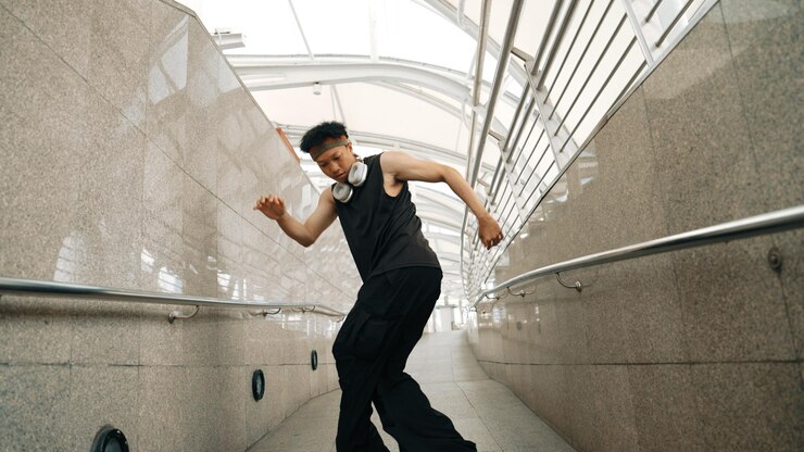 Foto hipster habilidoso e bonito realizam dança de rua no corredor estreito sprightly