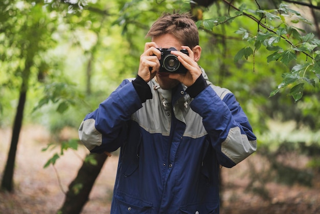 Un hipster haciendo fotos usando una vieja cámara vintage al aire libre