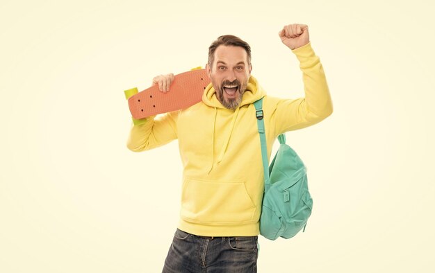 Hipster de hombre maduro guapo feliz con mochila y tablero de centavo aislado en skater blanco