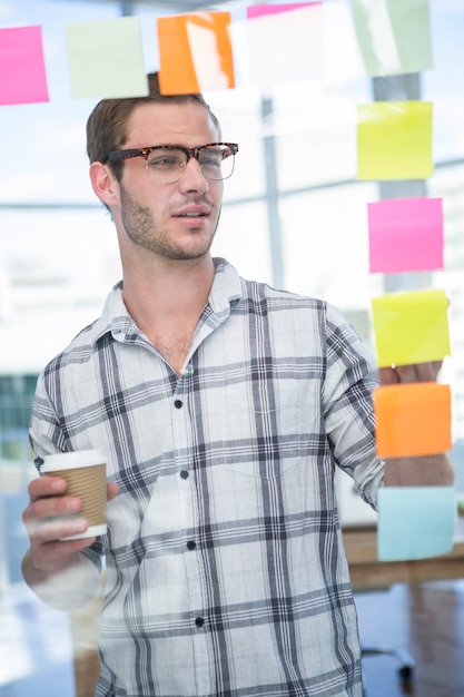 Hipster hombre mirando post-it en la oficina