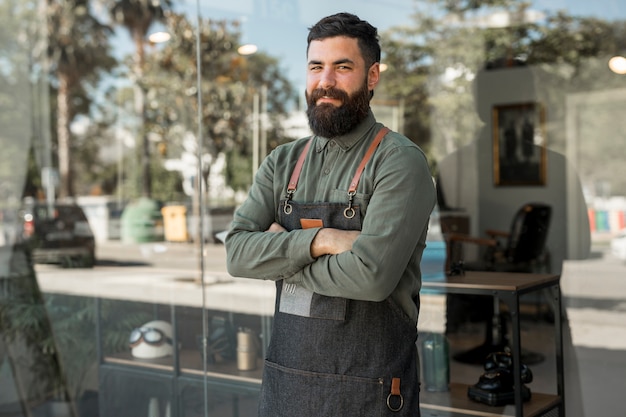 Hipster hombre peluquero de pie cerca de barbería