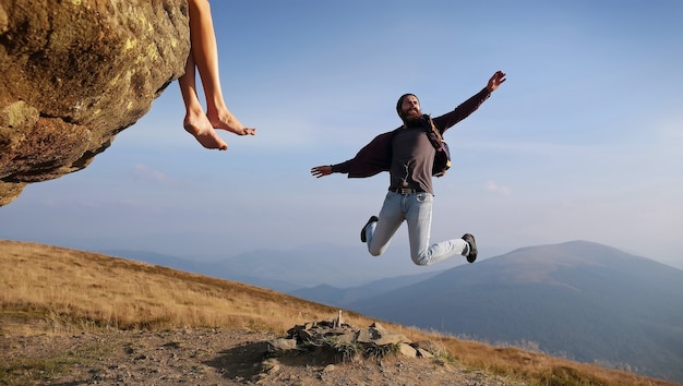 Hipster hombre saltando en la montaña en el cielo azul