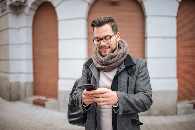 Hipster homem andando na cidade e digitar sms.