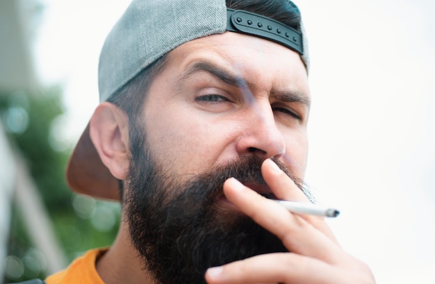 Foto hipster homem brutal fumando cigarro fumando vício