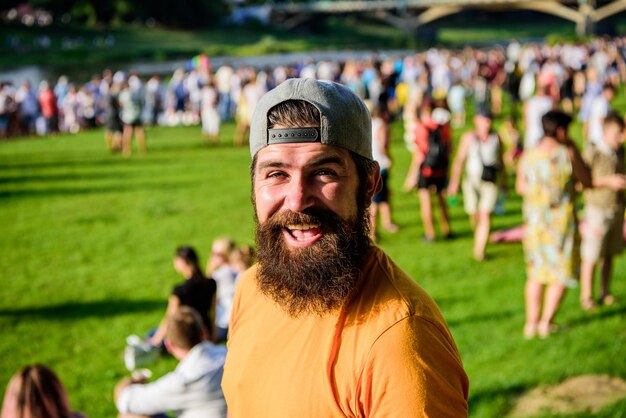 Hipster in Mütze feiern gerne Eventfest oder Festival. Mann bärtiger Hipster vor Publikum. Open Air Konzert. Fanbereich. Musikfestival. Unterhaltungskonzept. Besuchen Sie das Sommerfest. Sommerfest.