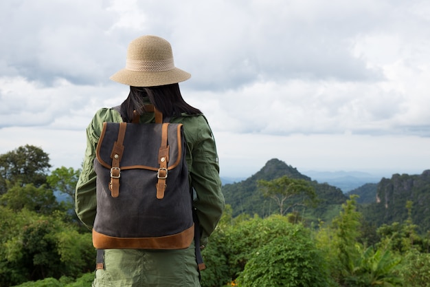 Hipster jovem com mochila curtindo. Viajante turista em fundo de montanha