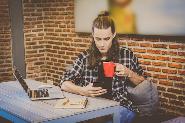 Foto hipster jovem freelancer usando telefone inteligente móvel