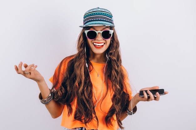 Hipster jovem mulher bonita em óculos de sol, vestindo boné e camiseta laranja