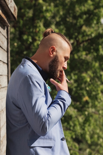 Foto hipster jovem olhando longe da câmera enquanto fumava um cigarro