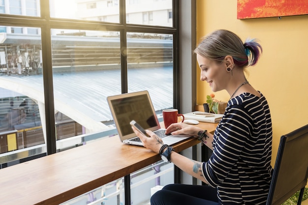 Hipster joven mujer independiente que usa teléfono móvil inteligente