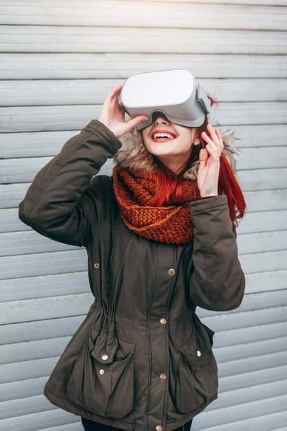 Foto hipster jovencita juega la aplicación de juegos móviles de realidad virtual en el teléfono inteligente conectado a las modernas gafas vr al aire libre