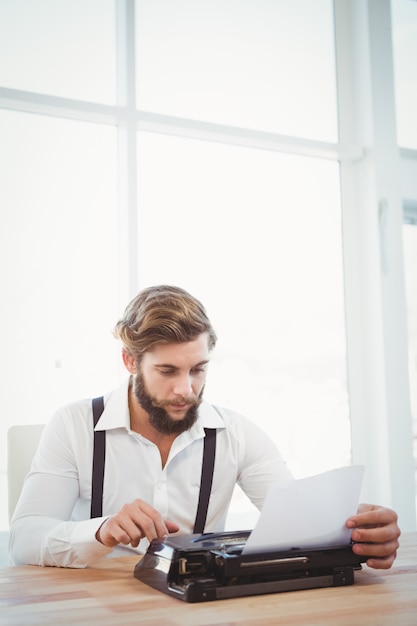 Hipster con máquina de escribir en el escritorio en la oficina