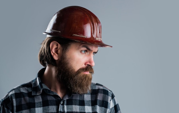 Hipster masculino barbudo en camisa a cuadros y taller de herramientas de casco de trabajador