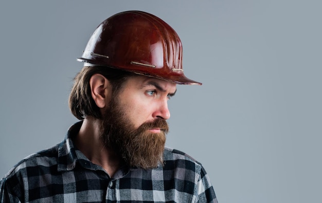 Hipster masculino barbudo em camisa quadriculada e loja de ferramentas de capacete de trabalhador