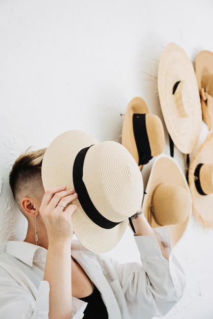 Hipster moderne Frau und viele Strohhüte wie Interieur schmücken die Wände in der Wohnung