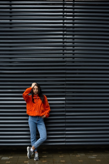 Hipster de mujer de moda joven descansando caminando al aire libre en la ciudad cerca de la pared