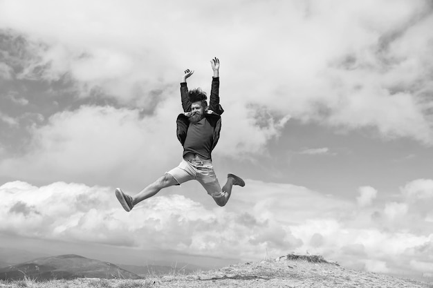 Hipster ou macho brutal conquista montanha homem com aparência brutal salta conceito de liberdade homem com barba desfruta de liberdade pulando no topo da montanha hipster se sente livre enquanto caminha no fundo do céu