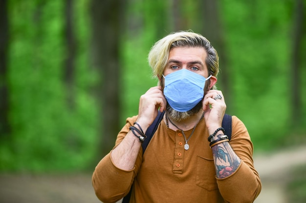 Hipster protegiéndose de la contaminación del aire o infección por virus coronavirus El hombre disfruta de la naturaleza usando mascarilla Detener la infección Salir lentamente de las restricciones de bloqueo Caminar en el parque Evitar la infección