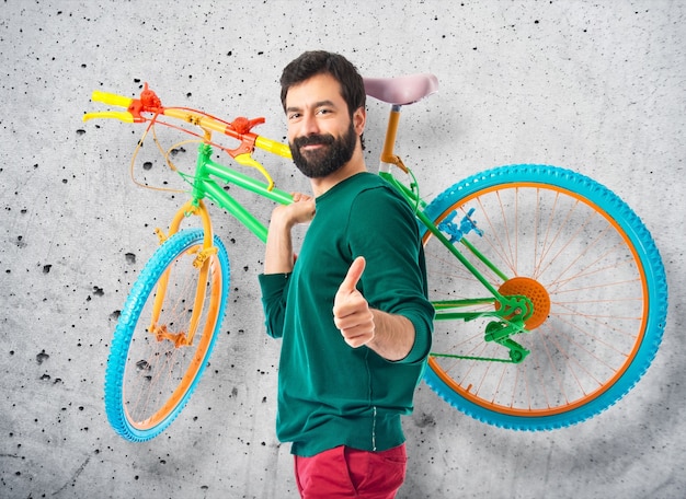 Foto hipster con el pulgar arriba sosteniendo una bici