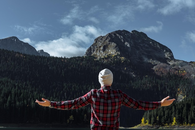 Foto hipster-reisender hob die hände gegen den black lake durmitor national park zabljak montenegro