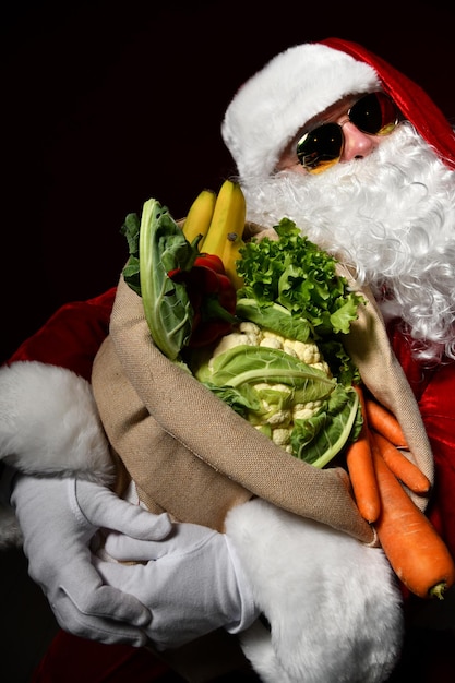 Hipster Santa Claus hält einen großen Sack voller Obst und Gemüse