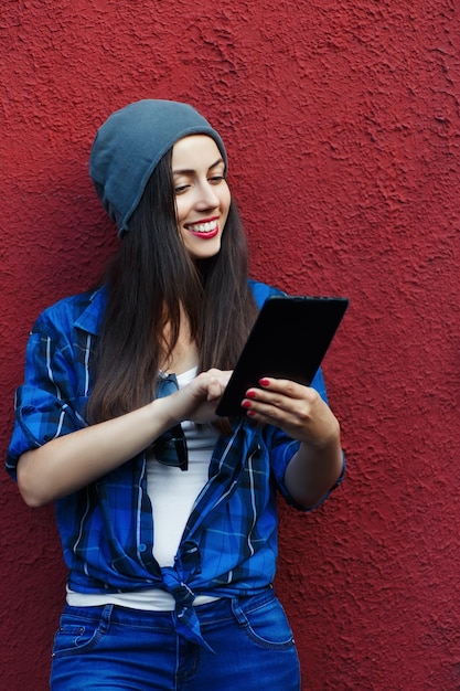 Hipster sorridente segurando um tablet ao ar livre