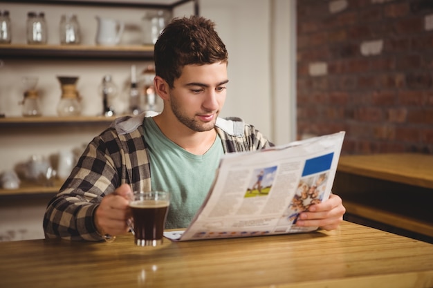 Foto hipster tomando café y leyendo el periódico