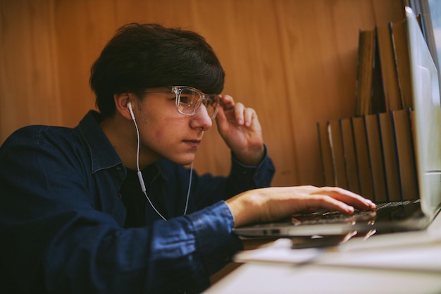 Hipster-Typ mit Brille, der sich ein Schulungs-Webinar auf einem Laptop ansieht Online-Schulung für Fernunterricht