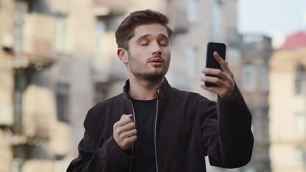 Hipster-Typ telefoniert draußen per Videoanruf. Schöner Mann, der draußen auf den Bildschirm schaut