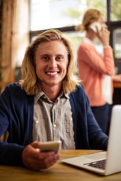 Hipster usando una computadora portátil y un teléfono inteligente