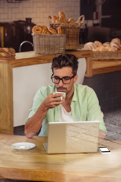 Hipster usando um laptop enquanto bebia café