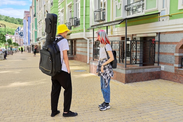 Hipsters adolescentes na moda menino e menina andando falando na rua da cidade, menino com guitarra no caso. juventude, estilo de vida, criatividade, comunicação, conceito de amizade