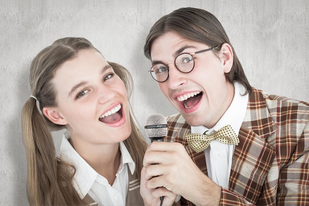 Hipsters nerds felizes cantando com microfone contra fundo branco