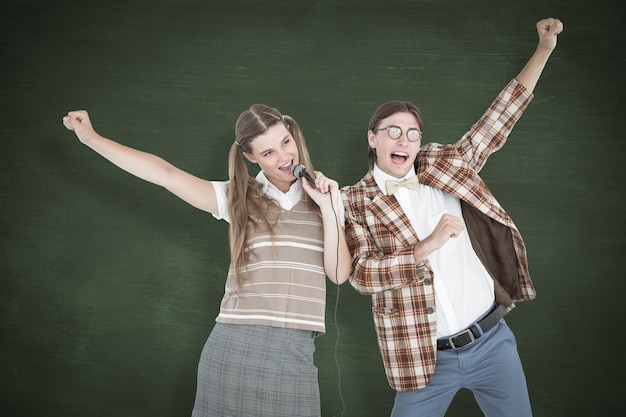 Hipsters nerds felizes cantando com microfone contra lousa verde