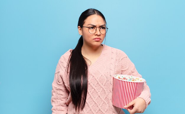 Hispanic Frau fühlt sich traurig, verärgert oder wütend und schaut mit einer negativen Einstellung zur Seite, runzelt die Stirn vor Uneinigkeit