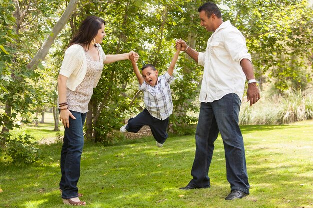 Hispanic Mutter und Vater Swinging Sohn im Park