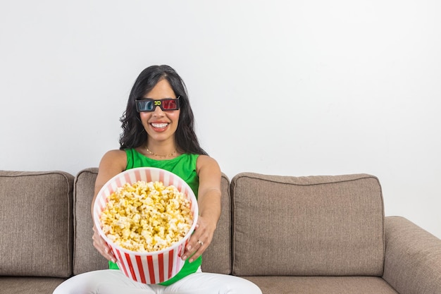 Hispanische Frau, die der Kamera Popcorn zeigt