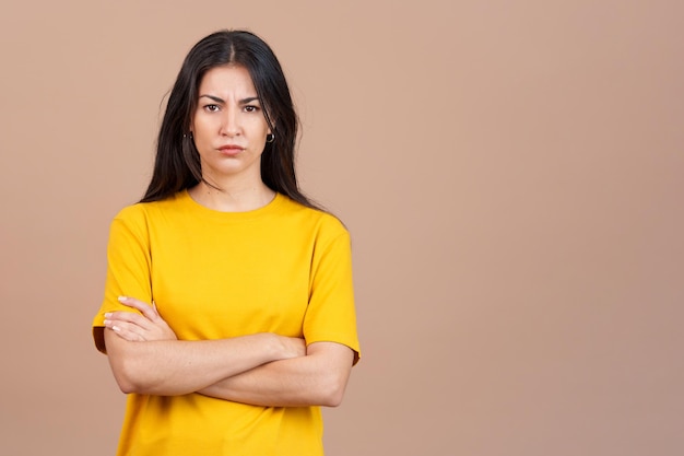 Hispanische Frau, die die Arme mit einem wütenden Ausdruck kreuzt