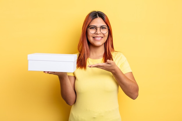 Hispanische Frau, die fröhlich lächelt, sich glücklich fühlt und ein Konzept zeigt. leeres Verpackungskonzept