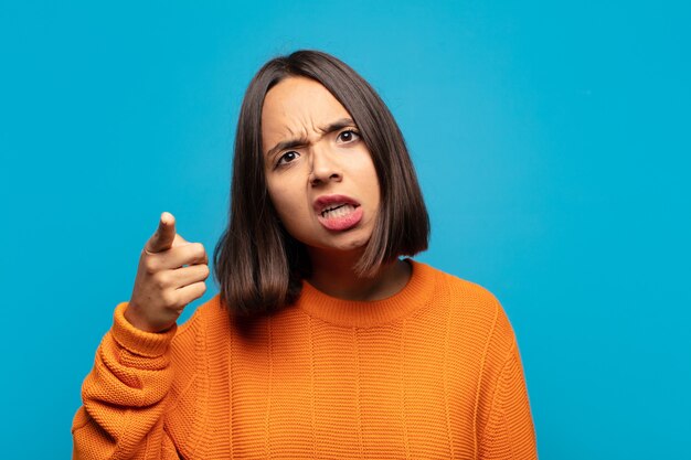 Hispanische Frau, die mit einem wütenden aggressiven Ausdruck auf Kamera zeigt, der wie ein wütender, verrückter Chef aussieht